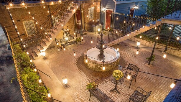 A courtyard with a central fountain, outdoor seating, and a staircase leading to upper levels. - Quaint Studio w/ Courtyard, 4 Blocks from River Street by Lucky Savannah (Savannah)
