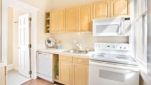 A kitchen with wooden cabinets, a microwave, a stove, and a dishwasher. - Quaint Studio w/ Courtyard, 4 Blocks from River Street by Lucky Savannah (Savannah)