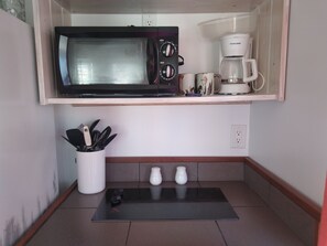 Une petite cuisine équipée d’un four à micro-ondes, d’une machine à café et d’ustensiles de cuisine.