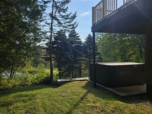 Relax in a serene outdoor setting with a hot tub and lush greenery.