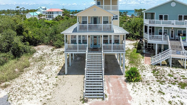 A two-story beachfront house with a balcony, a covered porch, and a staircase leading to the entrance. - Steps From The Oceanfront! Pool, Pet Friendly, Wifi, king beds! WEEKLY DISCOUNTS (Cape San Blas)