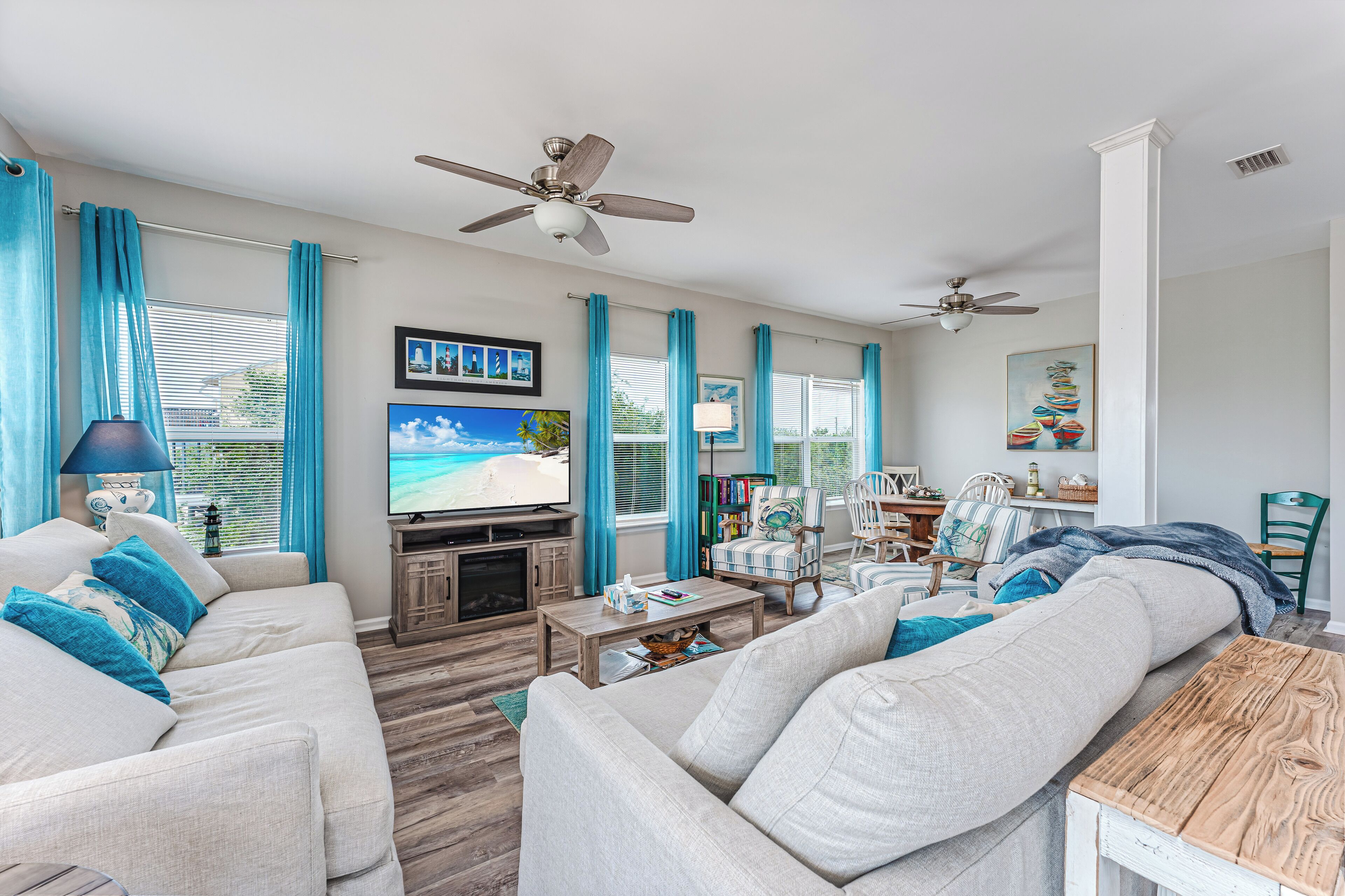 A living room with a sofa, a coffee table, a TV, and a ceiling fan.