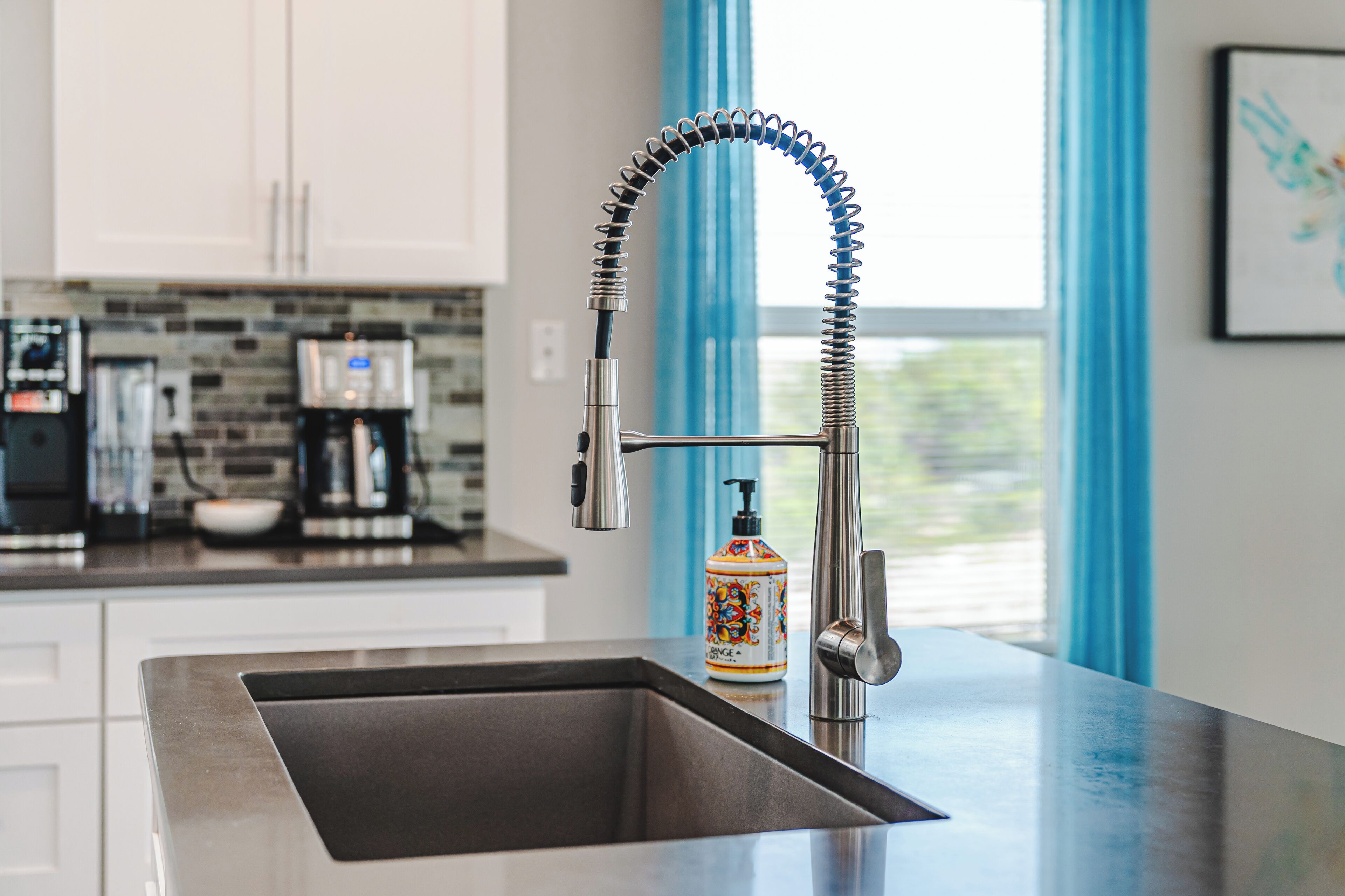 A modern kitchen with a stainless steel sink, a flexible faucet, and a coffee machine.