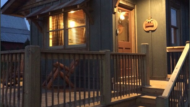 Un chalet rustique doté d’une terrasse en bois, d’une enseigne accueillante et d’un escalier menant à l’entrée.