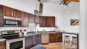 Een moderne keuken met donker houten kastjes, roestvrijstalen apparatuur en een bar met krukken.