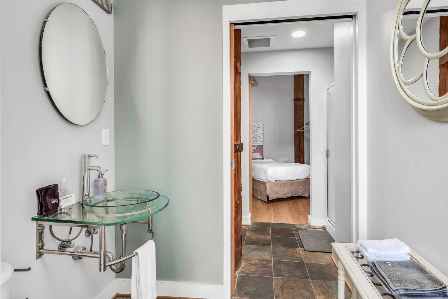 Une salle de bain moderne avec un lavabo en verre, un miroir et un porte-serviettes.