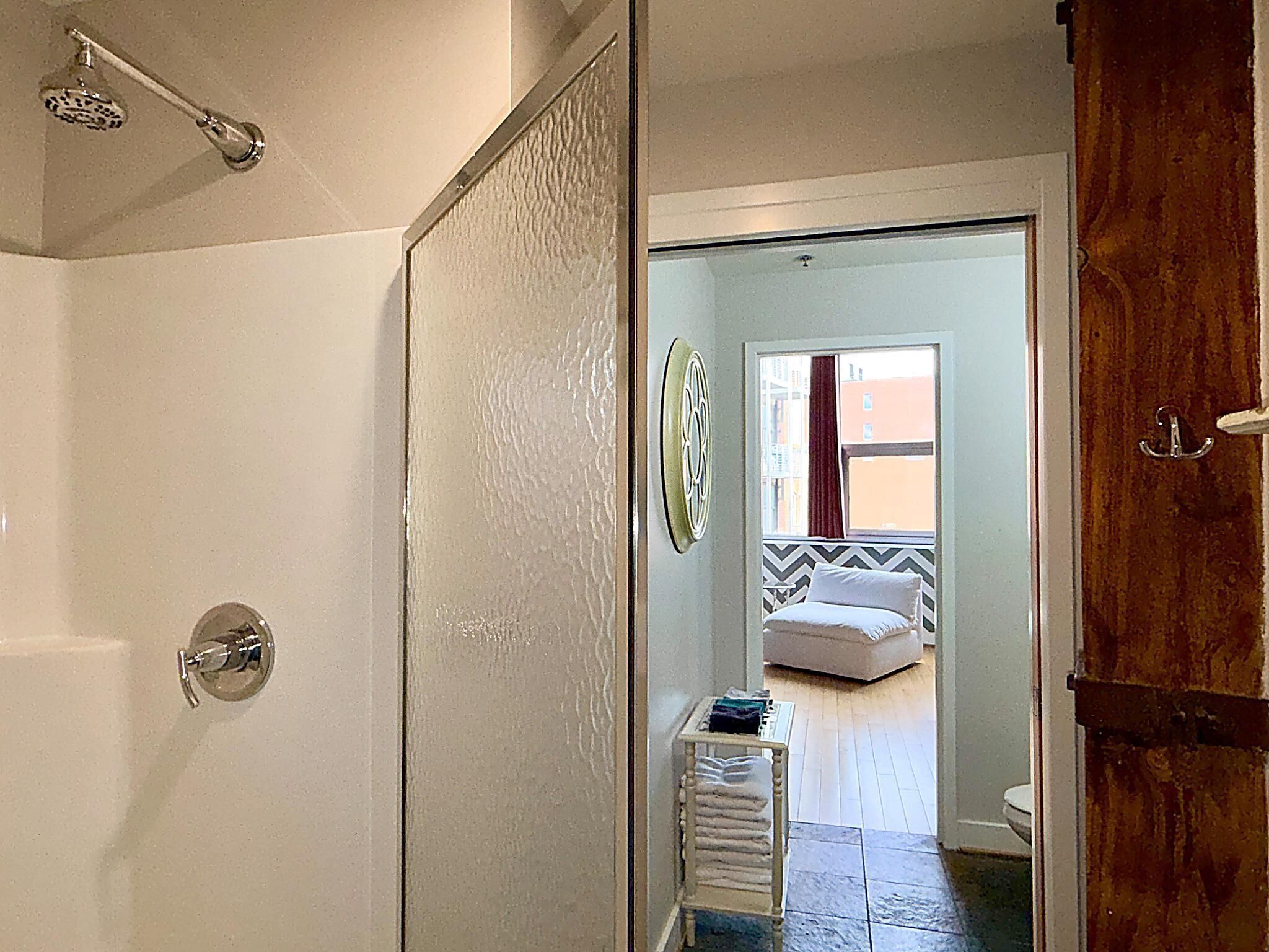 Une salle de bain avec une douche, des toilettes et une petite table avec des serviettes.