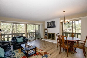 A living room with a fireplace, a dining table with chairs, a sofa, and a coffee table.
