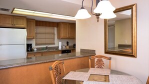 Eine Küche mit Holzausstattung, einem Kühlschrank, einer Arbeitsplatte, einem Spülbecken und einem Essbereich mit Tisch und Stühlen.