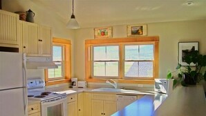 A kitchen with white cabinets, a stove, a sink, and a microwave. - Award Winning Cow Creek Suite: Edge-Of-Town Quiet & Convenience With Great Views (Ridgway)