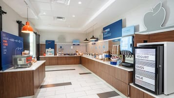 A modern breakfast area with a counter, a coffee machine, and a refrigerator labeled 'YOGURT EGGS MILK'.