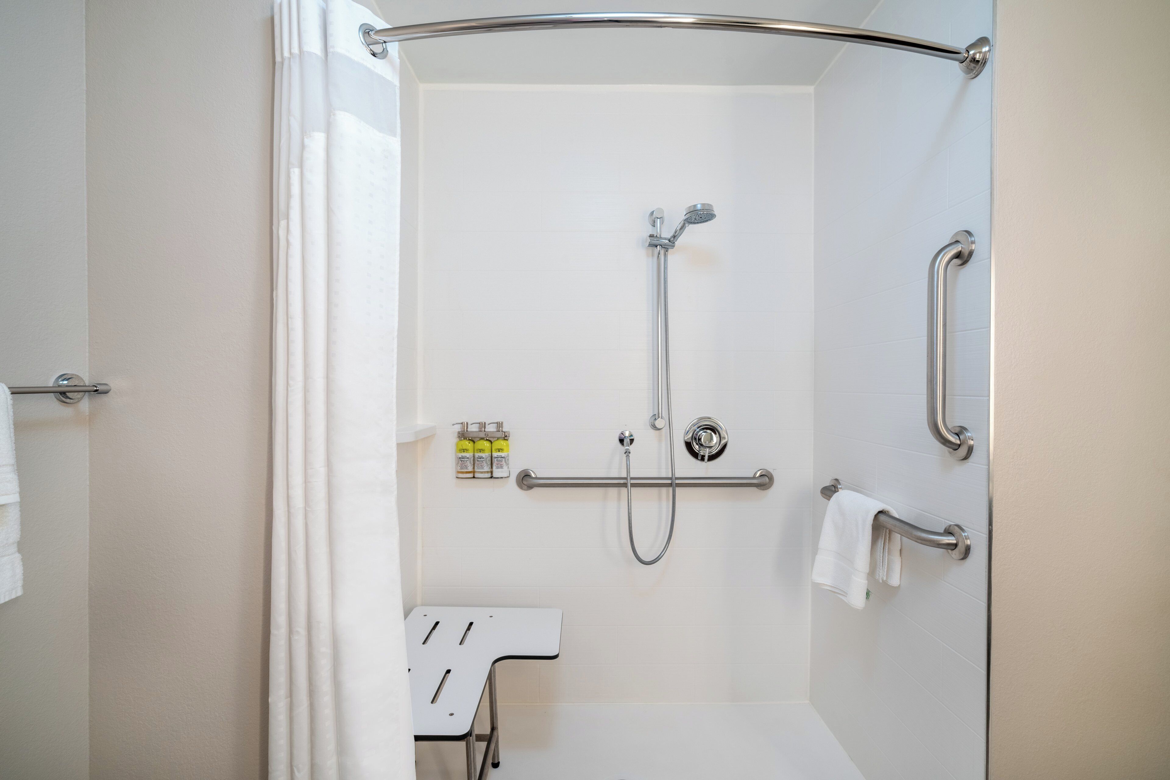 A shower area with a handheld showerhead, a handheld showerhead, and a towel rack.
