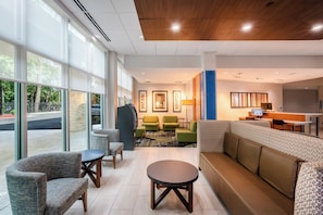 Un hall de hotel con zona de estar, mostrador de recepción y vistas al exterior.