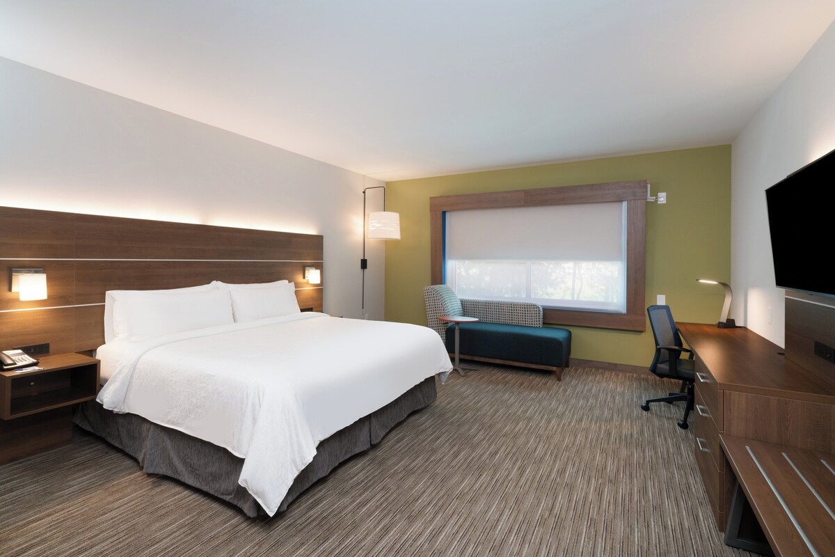 Ein Hotelzimmer mit einem großen Bett, einem Schreibtisch, einem Sessel, einer kleinen Couch und einem Fernseher.