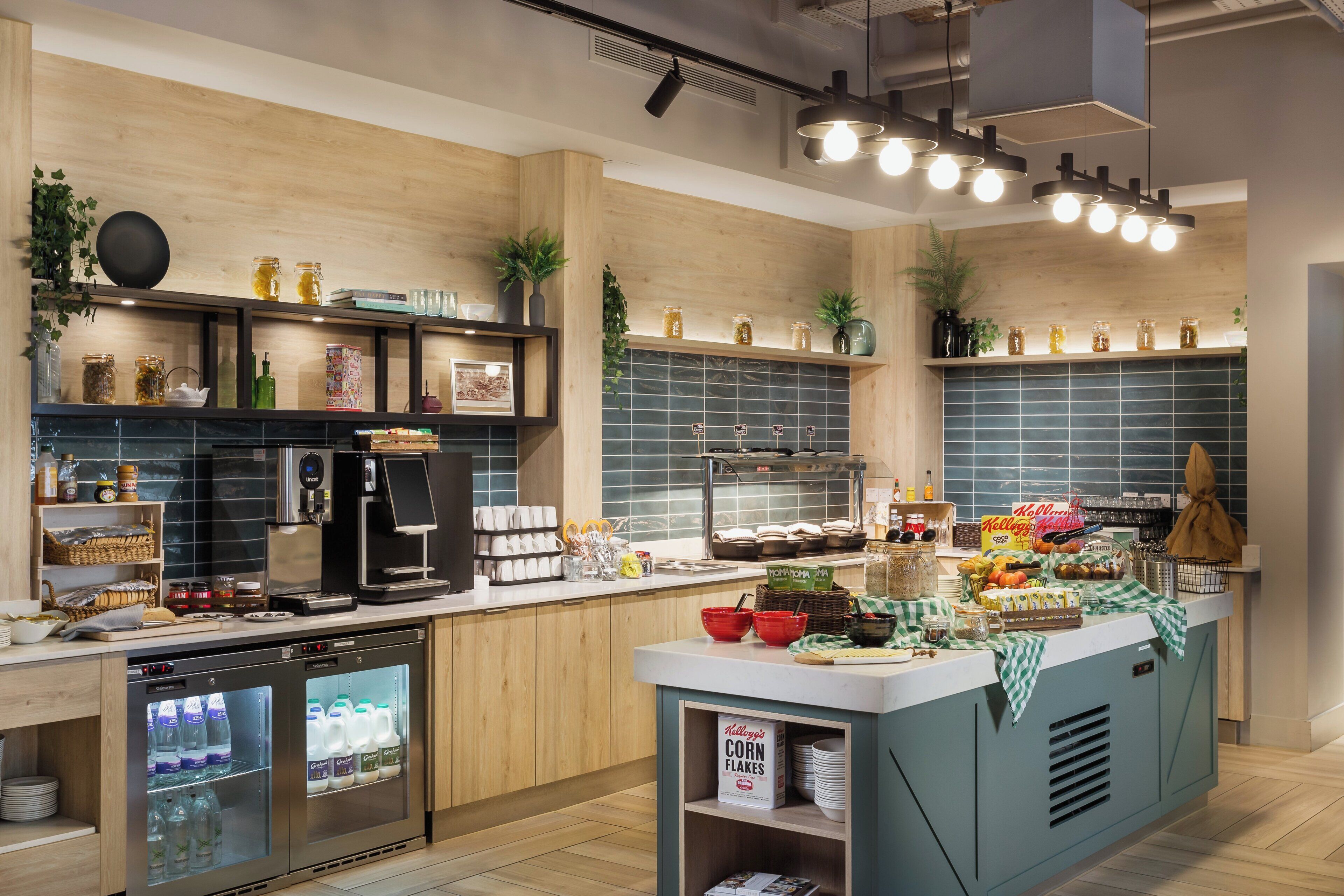 A modern kitchen with a coffee machine, a refrigerator, and a variety of food items on the counter.