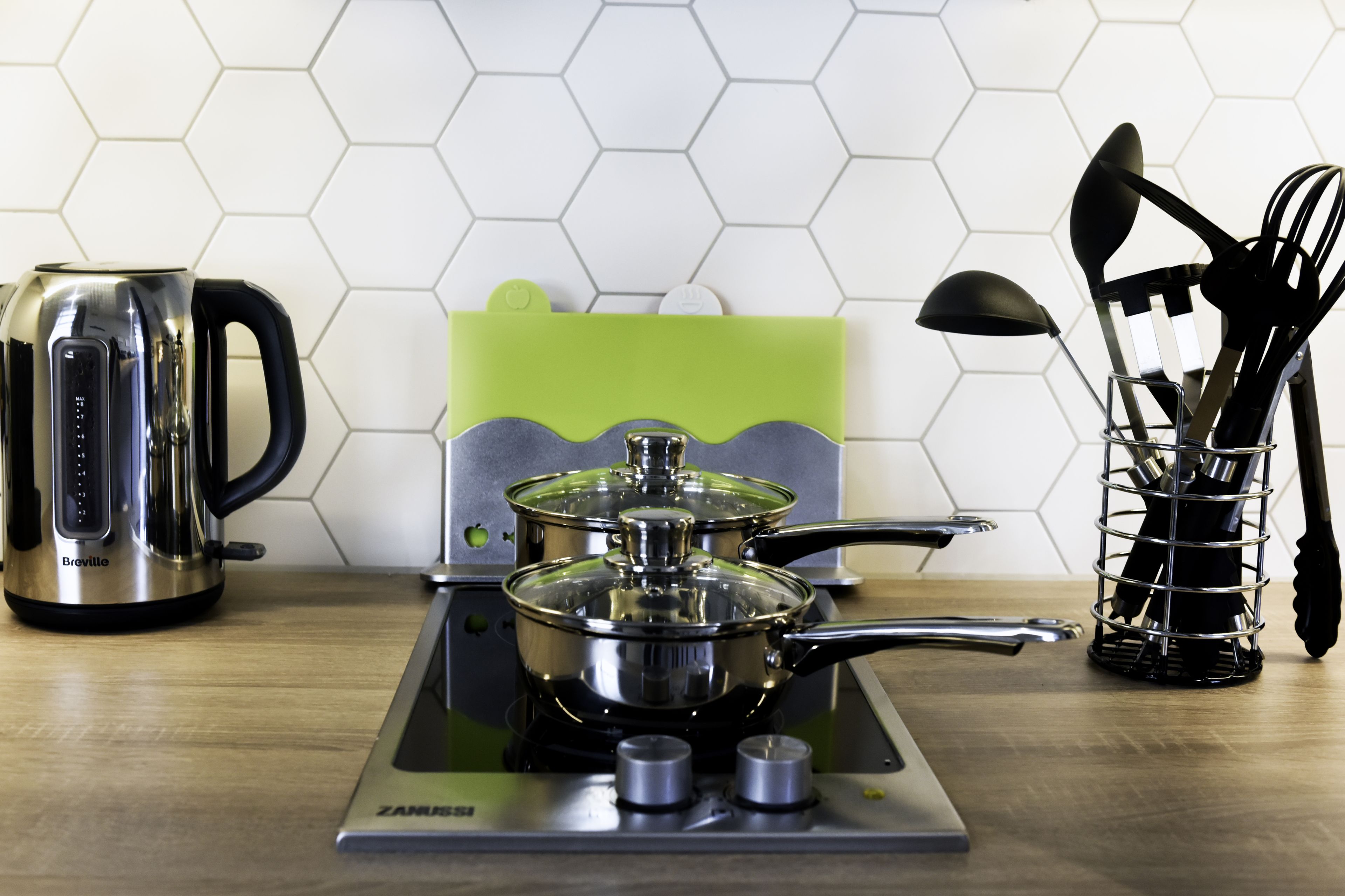 A kitchen with a Breville induction cooktop, a kettle, and a pot on the cooktop.
