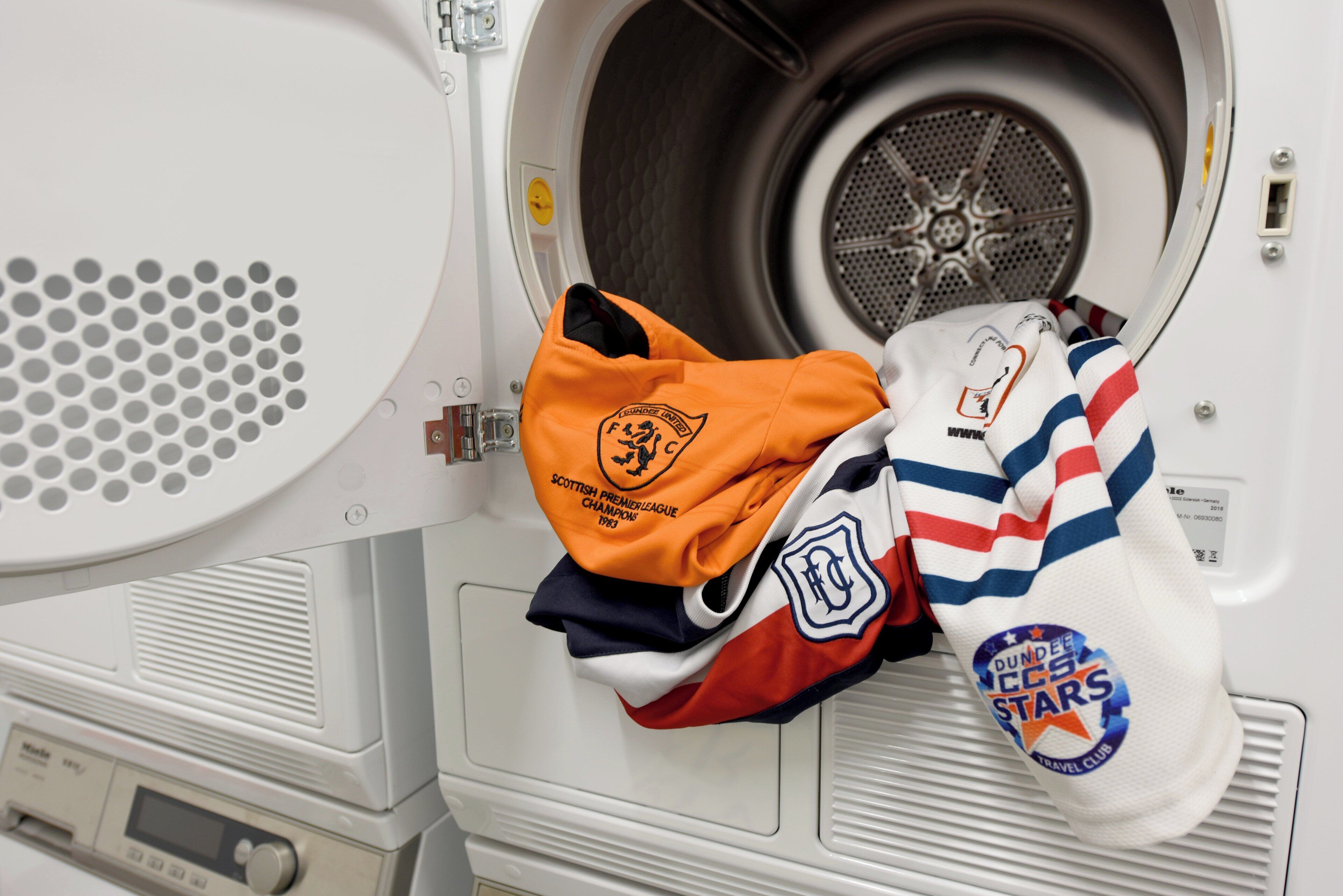 A front-loading washing machine with a front door open, revealing a white interior and a circular vent.