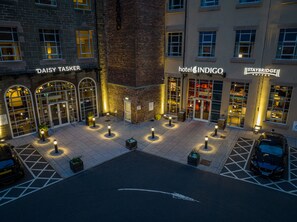 A hotel courtyard with 'Daisy Taser' and 'Hotel Indigo' signage, a parking area, and a 'Staybridge' building. - Staybridge Suites Dundee by IHG (Dundee)