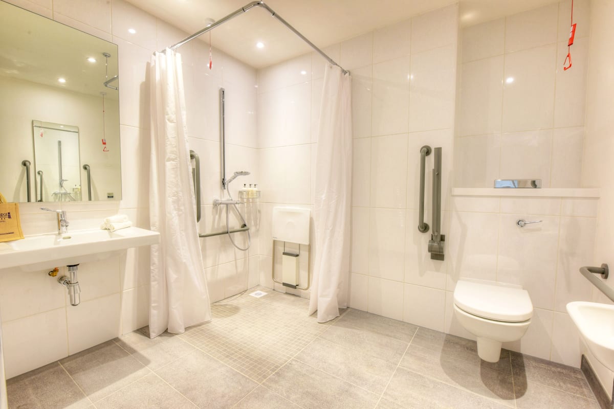 Un baño moderno con ducha, inodoro, lavabo y un espejo grande.