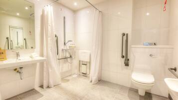Un baño moderno con ducha, inodoro, lavabo y un espejo grande.