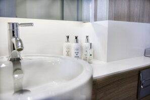 A modern bathroom with a white sink, chrome faucet, and wooden vanity. - Staybridge Suites Dundee by IHG (Dundee)