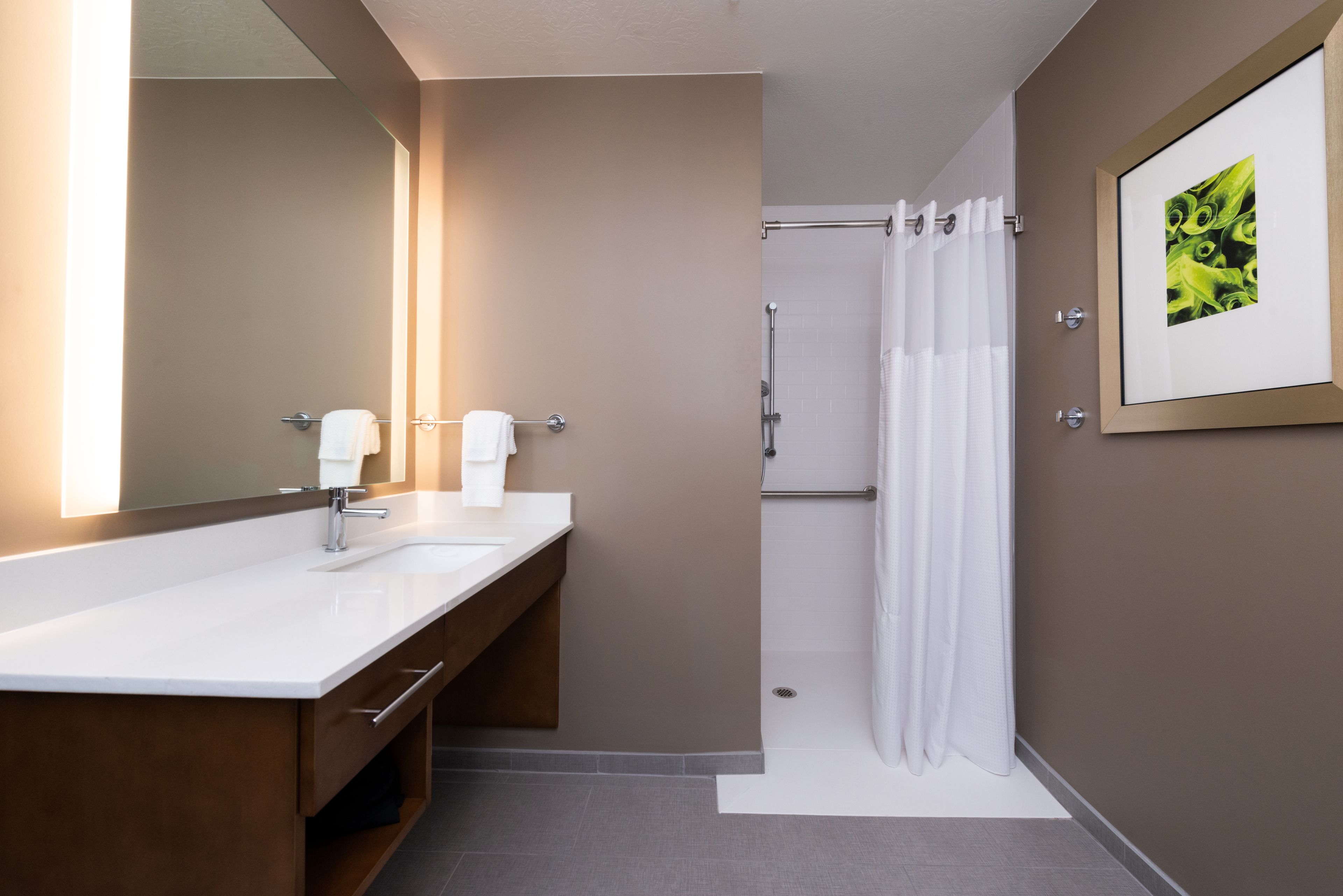 A modern bathroom with a double sink, a large mirror, and a shower area.