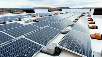 Paneles solares dispuestos en una azotea plana, con cielo despejado y montañas lejanas al fondo.