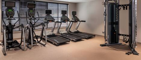 A gym with treadmills, elliptical machines, and a weightlifting station.