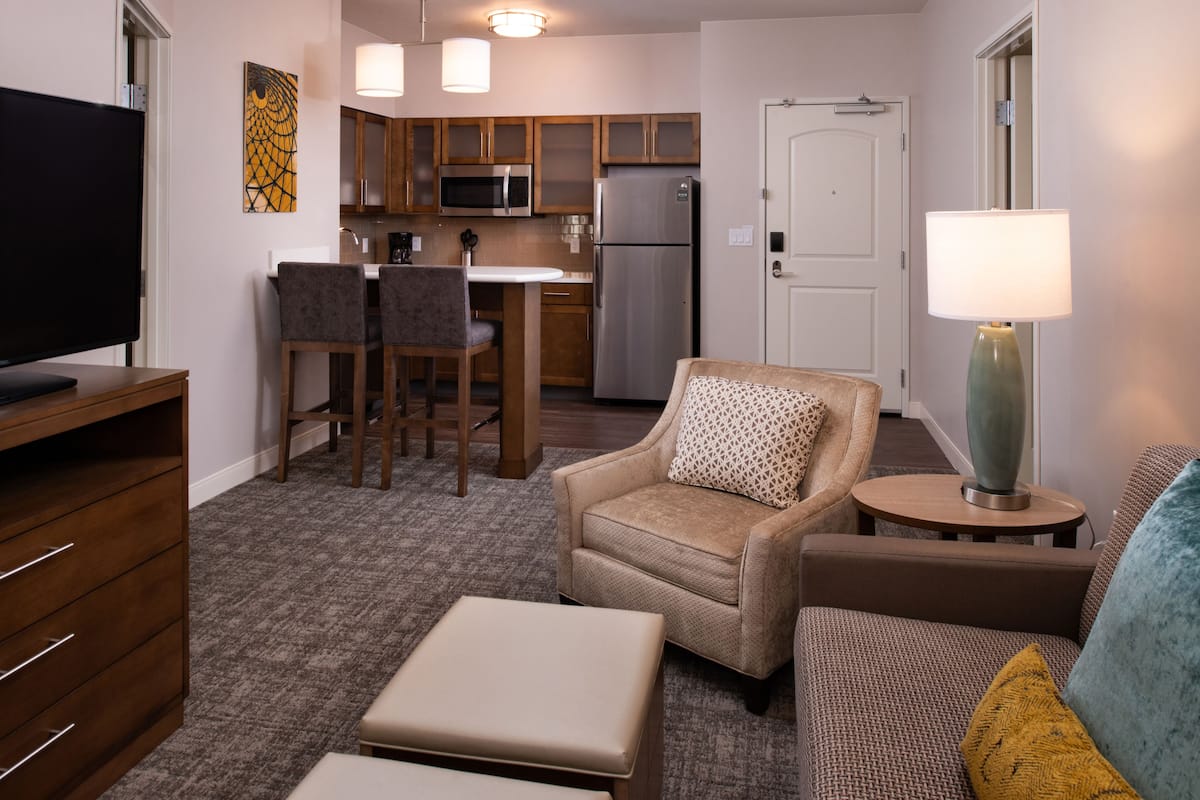 Un espacio habitable compacto con kitchenette, televisor, sofá y lámpara.