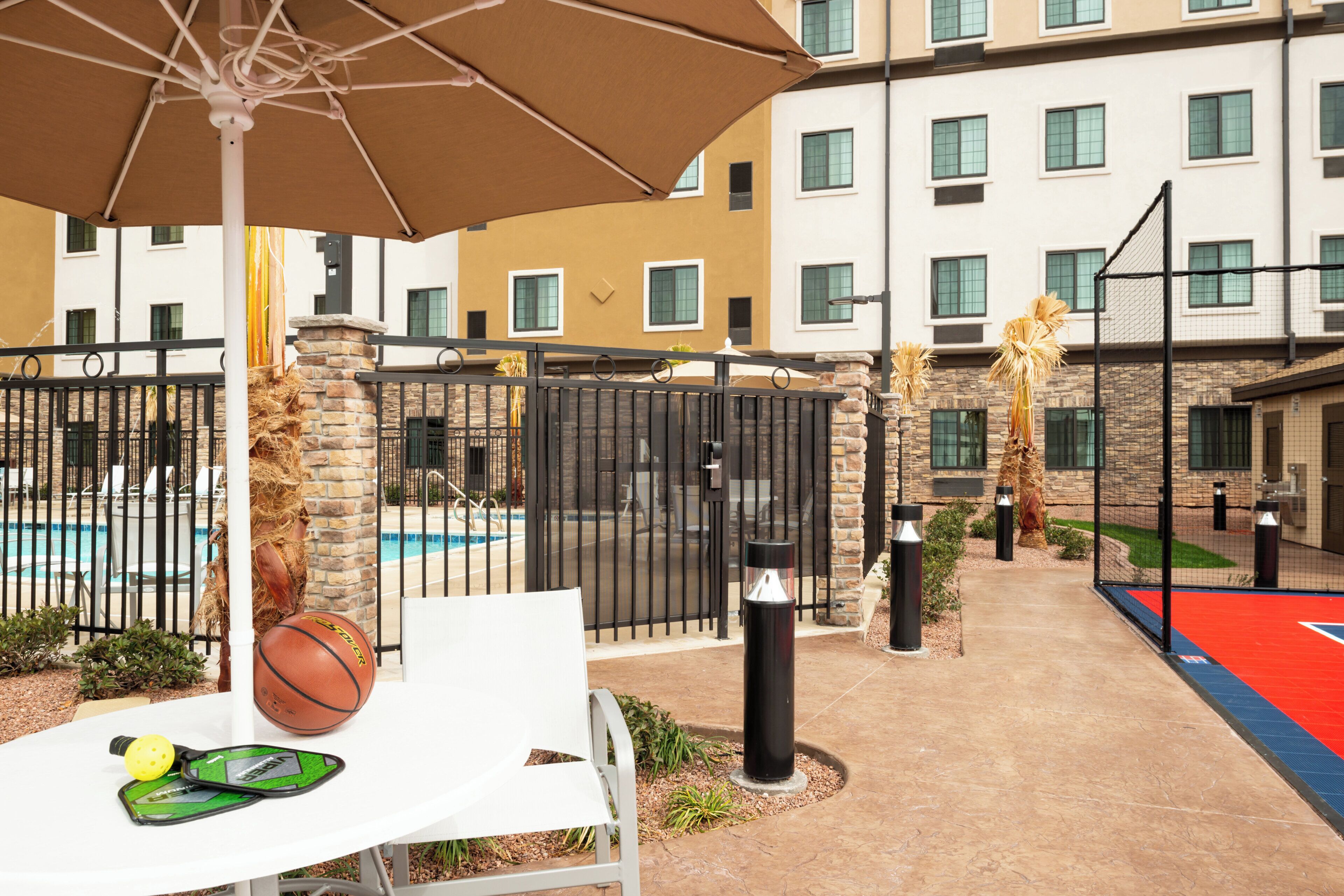 A pool area with a white table, a basketball, and a volleyball.