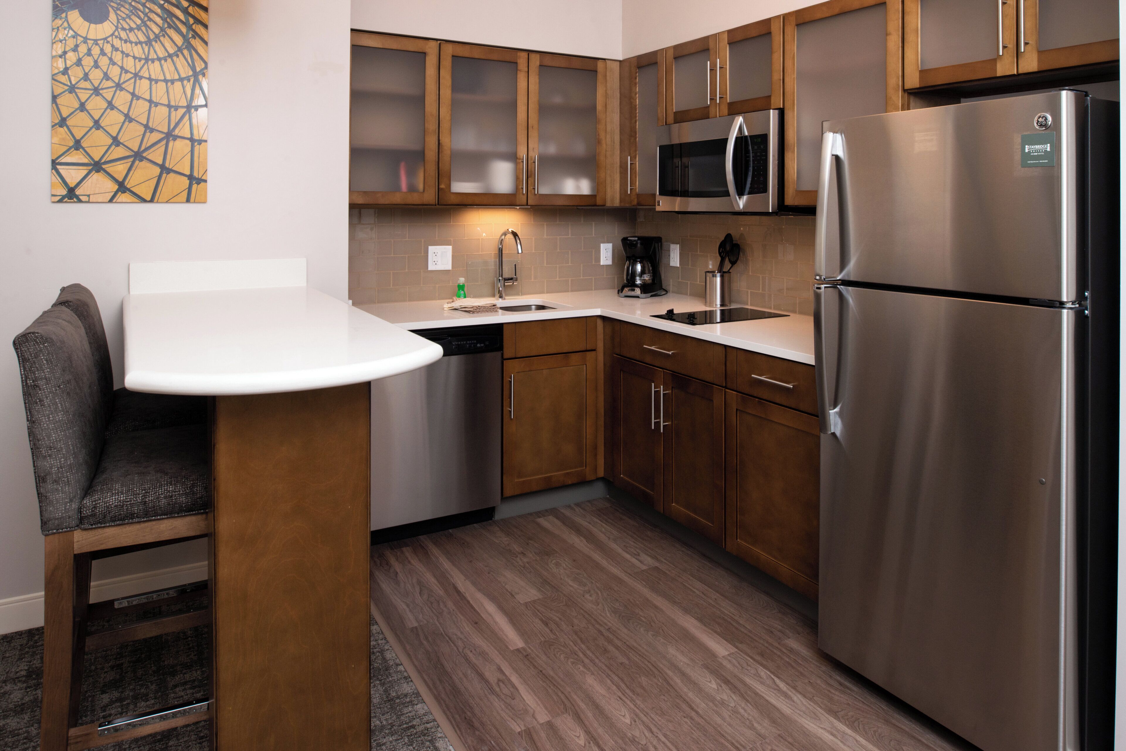 A modern kitchen with wooden cabinets, stainless steel appliances, and a white countertop.