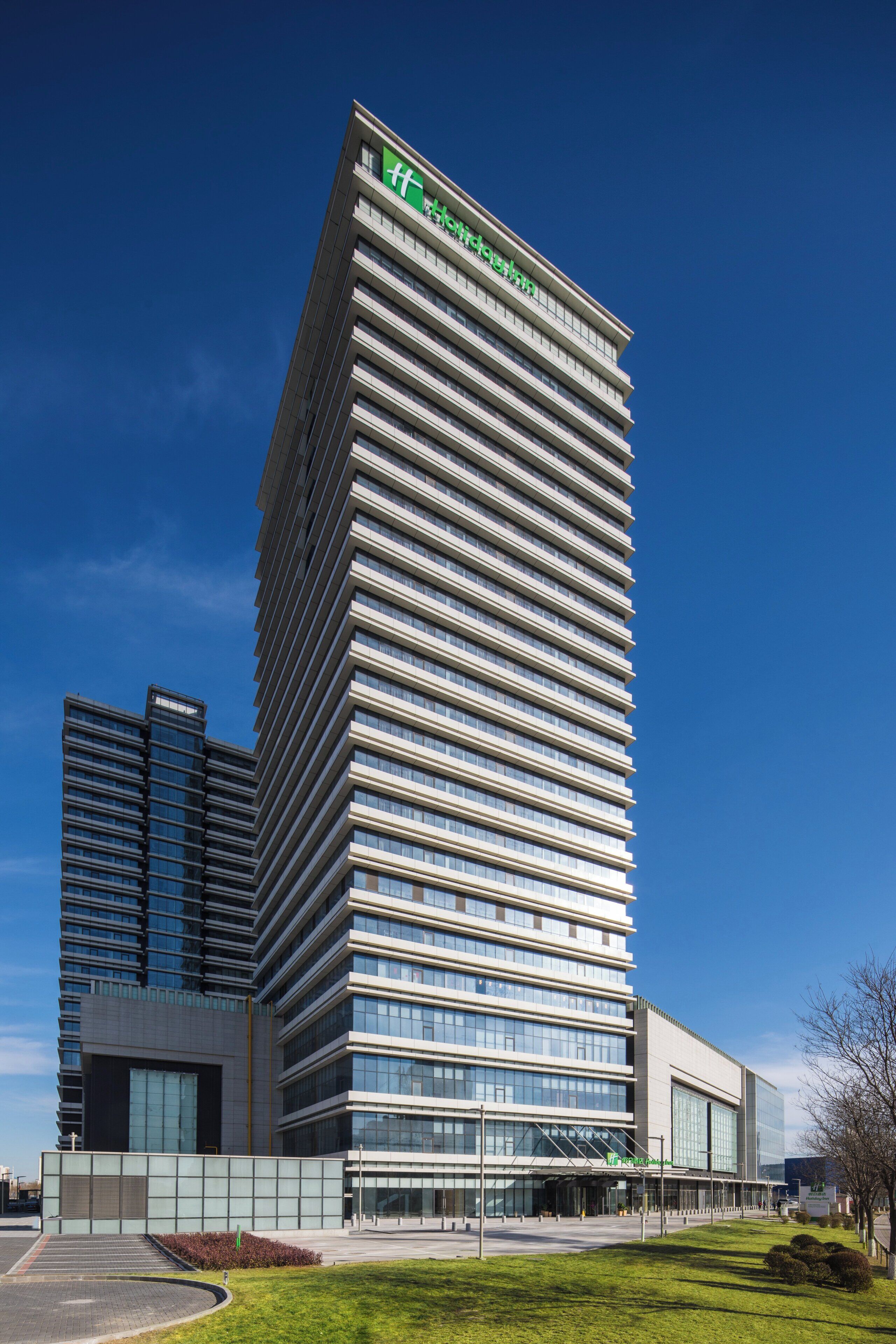 A modern hotel building with a prominent logo at the top, multiple floors, and a flat roof.