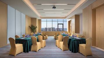 Un salón de conferencias con vistas a la ciudad, equipado con mesas, sillas y botellas de agua.