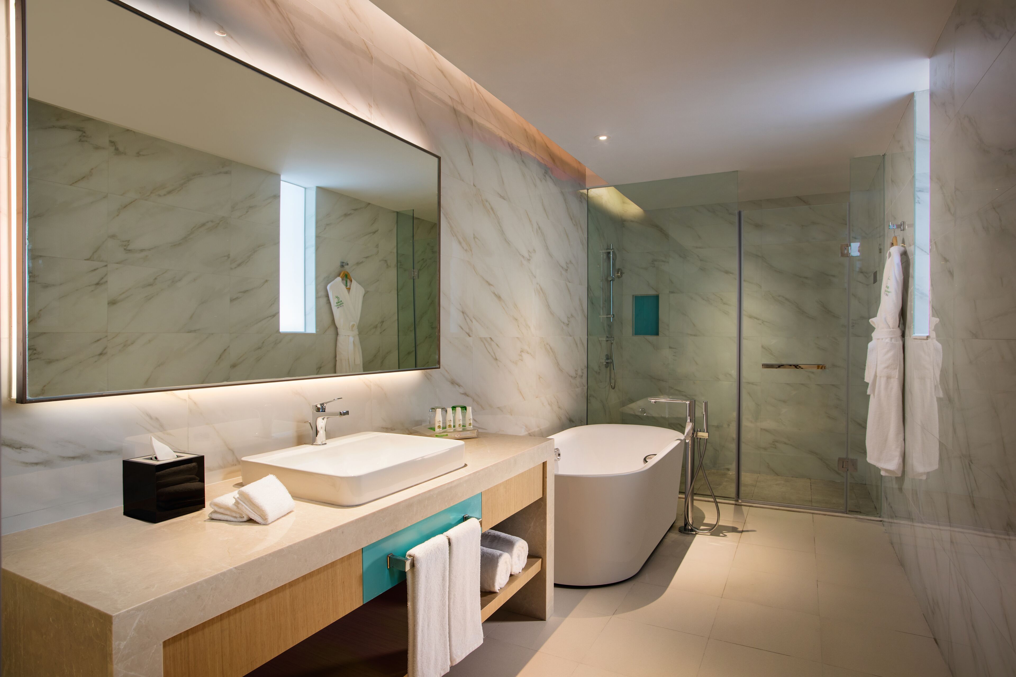 A modern bathroom with a large mirror, two sinks, a bathtub, and a glass-enclosed shower.