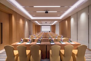 A conference room with rows of tables, chairs, and a projector screen at the front. - Holiday Inn Tianjin Xiqing by IHG (Tianjin)