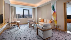 A hotel room with a large window, a sofa, a chair, a small table, and a TV. - Holiday Inn Tianjin Xiqing by IHG (Tianjin)