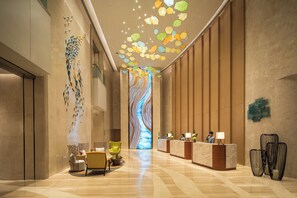 A hotel lobby with a reception desk, seating area, and a decorative ceiling. - Holiday Inn Tianjin Xiqing by IHG (Tianjin)