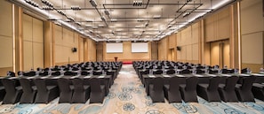 A conference room with rows of tables and chairs, a carpeted floor, and a projector screen at the front. - Holiday Inn Tianjin Xiqing by IHG (Tianjin)
