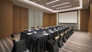 A conference room with a long table, chairs, and a projector screen.
