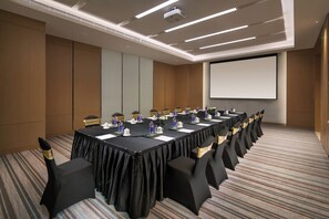 A conference room with a long table, chairs, and a projector screen. - Holiday Inn Tianjin Xiqing by IHG (Tianjin)