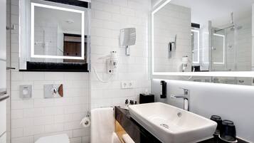Uma casa de banho moderna com uma pia branca, um espelho grande e uma sanita.