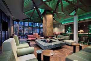 Un área de descanso moderna con asientos, una chimenea central y un bar con botellas.