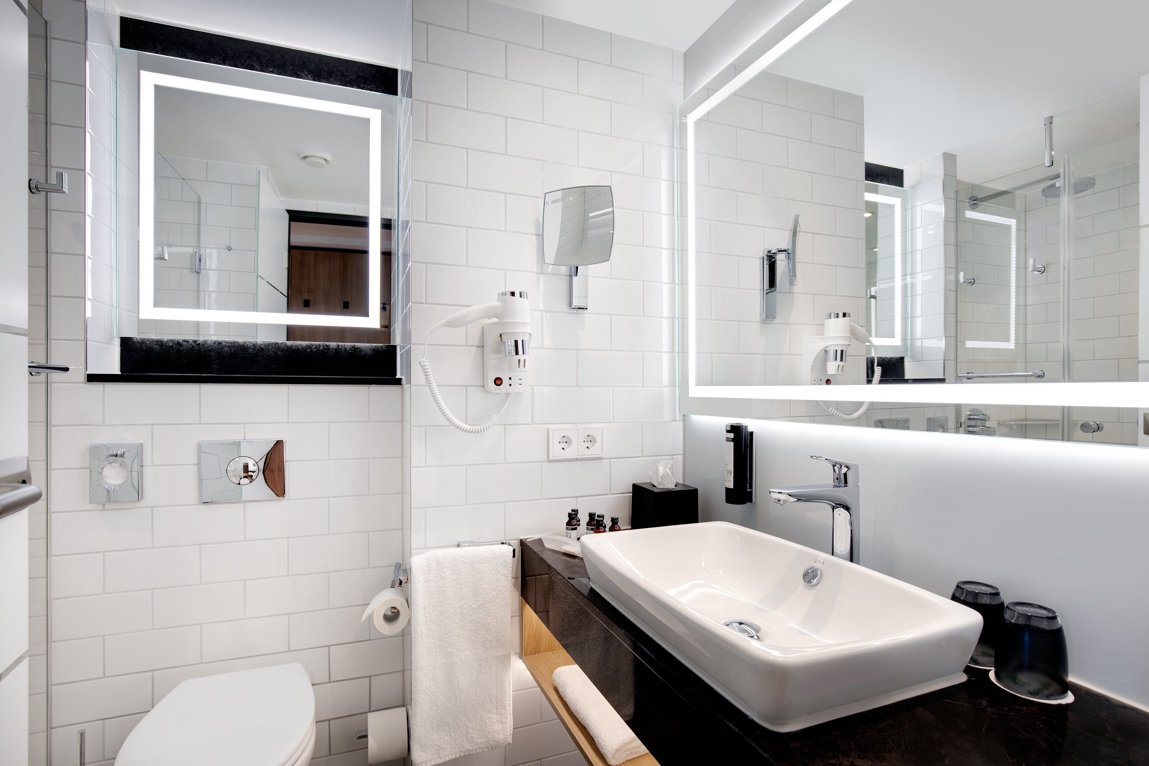 A modern bathroom with a white sink, a large mirror, and a glass-enclosed shower.