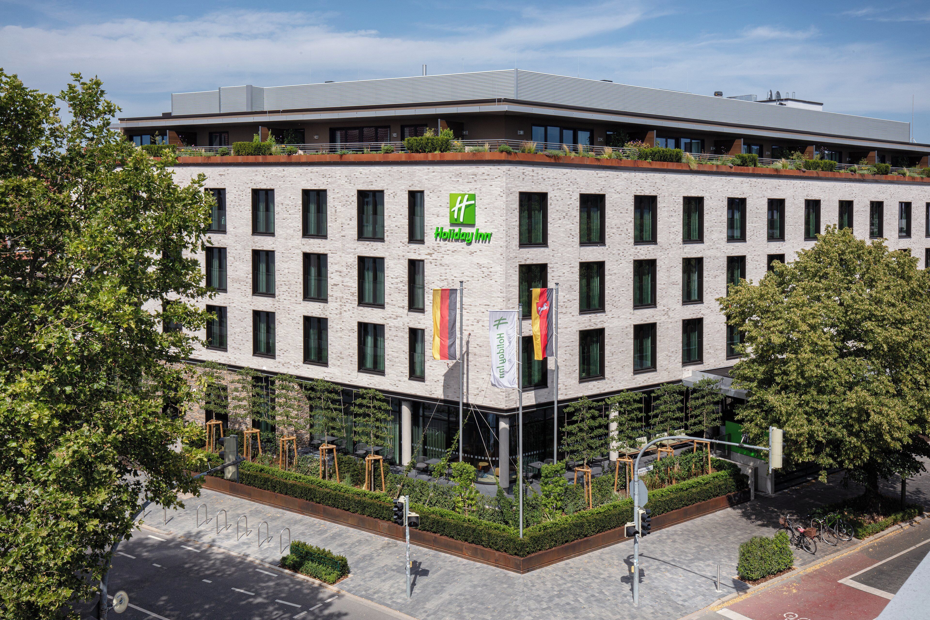 Un edificio moderno con techo plano, varias ventanas y un letrero de Holiday Inn.