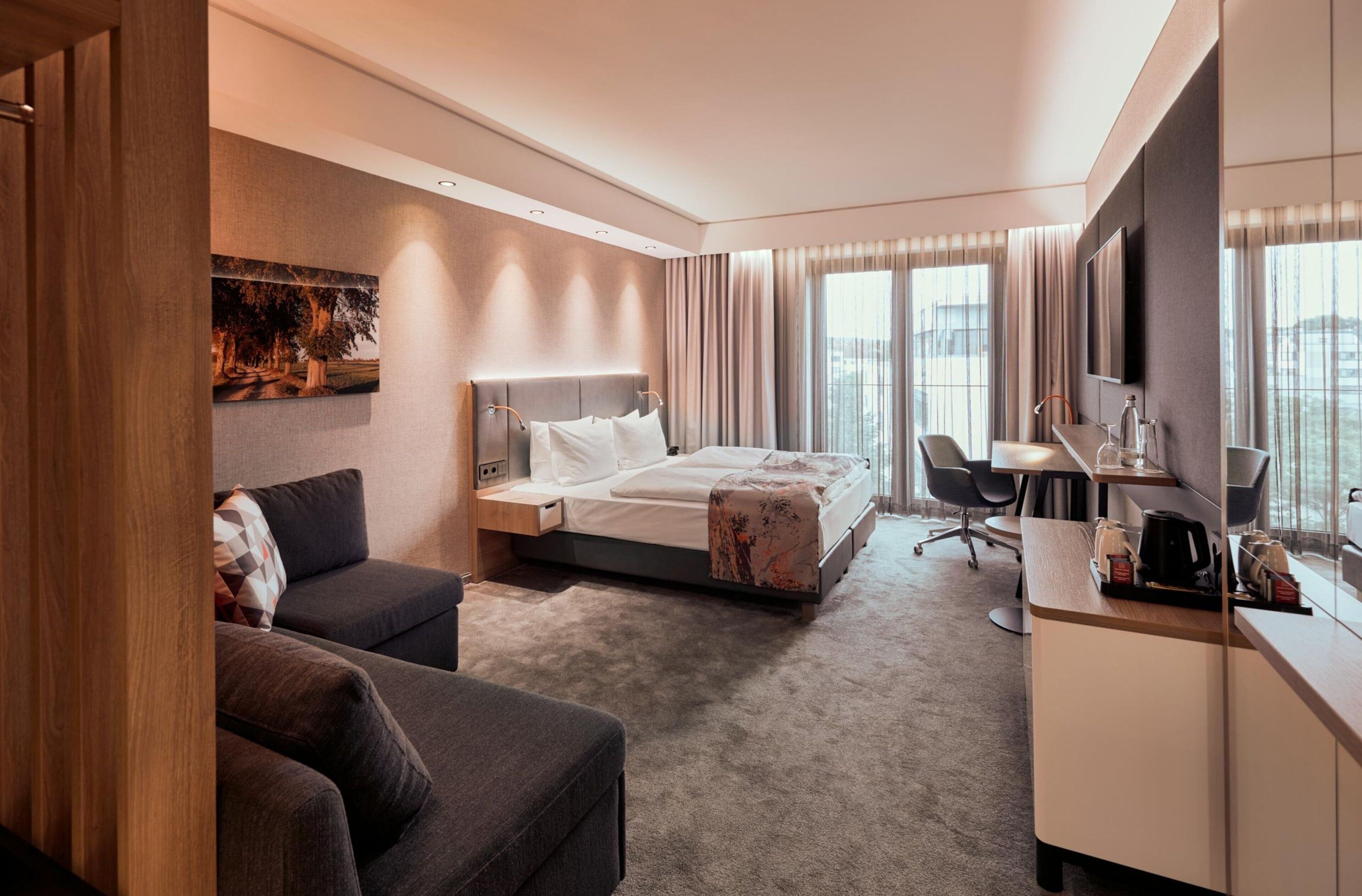 Una habitación de hotel con una cama, un escritorio, una silla, un sofá y un televisor.