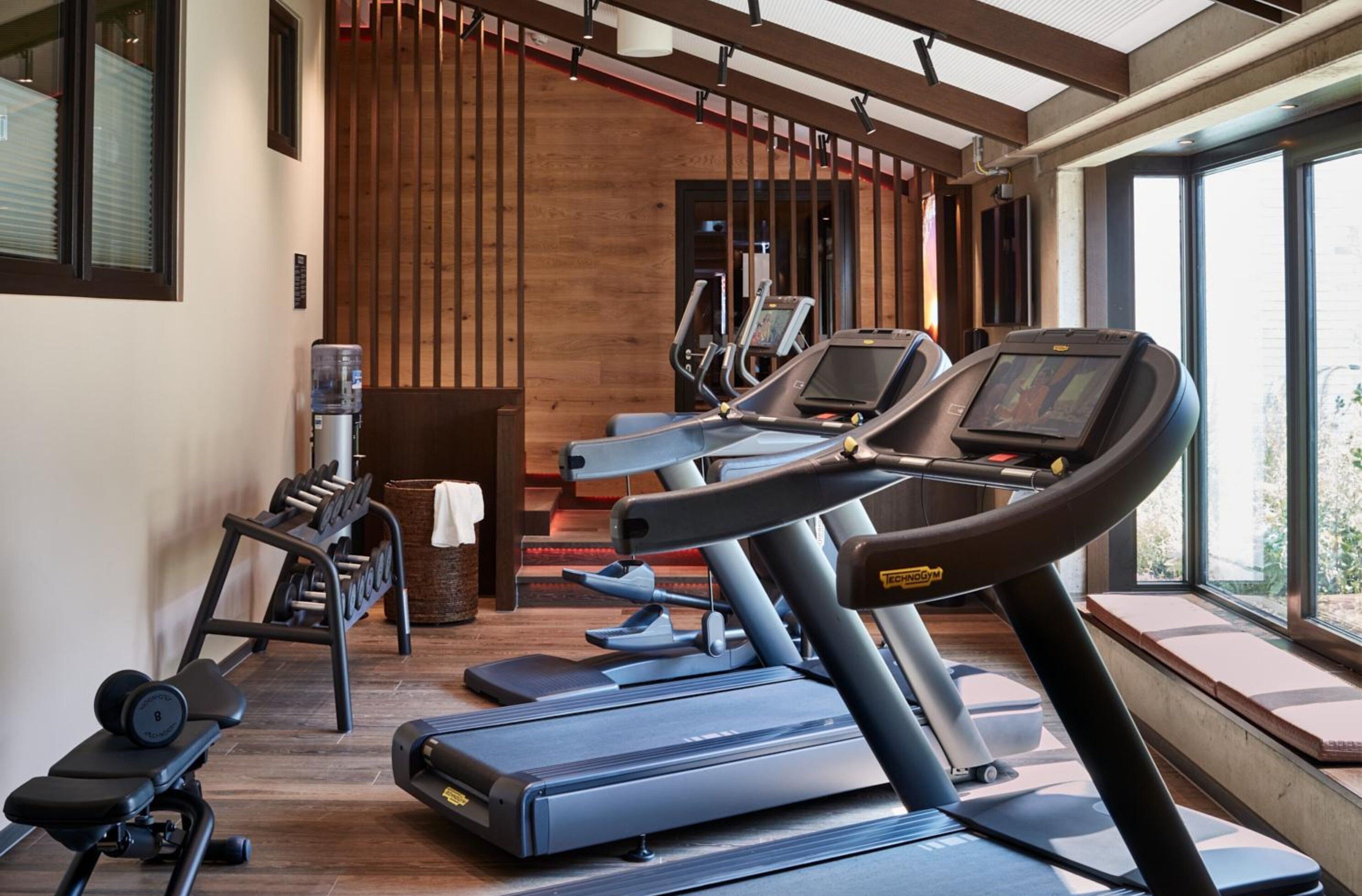 Ein Fitnessraum mit Laufbändern, einer Hantelbank und einem Wasserspender.