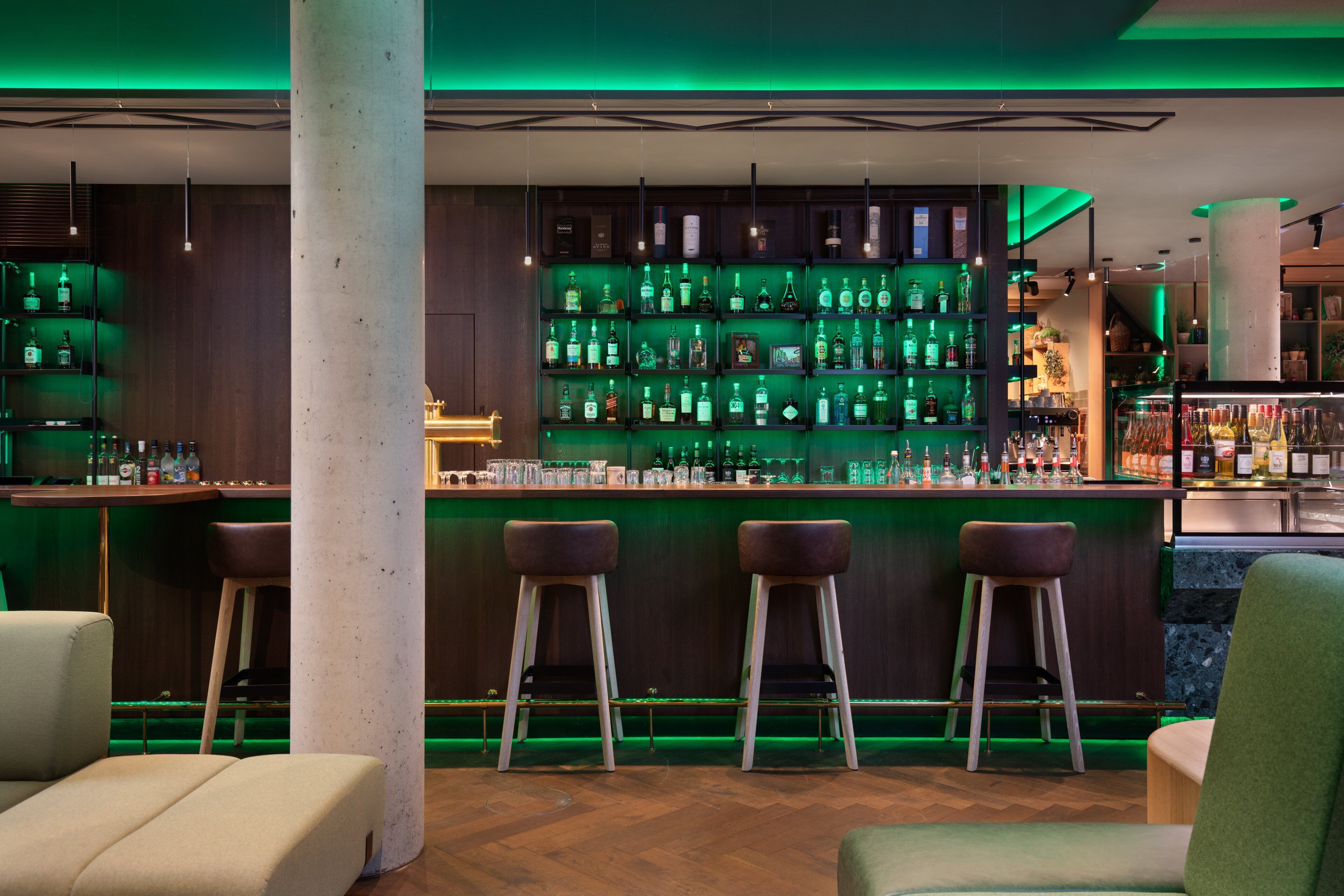 A bar area with multiple stools and shelves stocked with bottles.