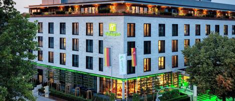 Un hotel con fachada moderna, múltiples ventanas y una entrada bien iluminada.