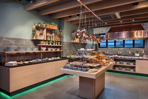 A buffet area with a variety of food options, a coffee station, and a kitchen visible in the background.