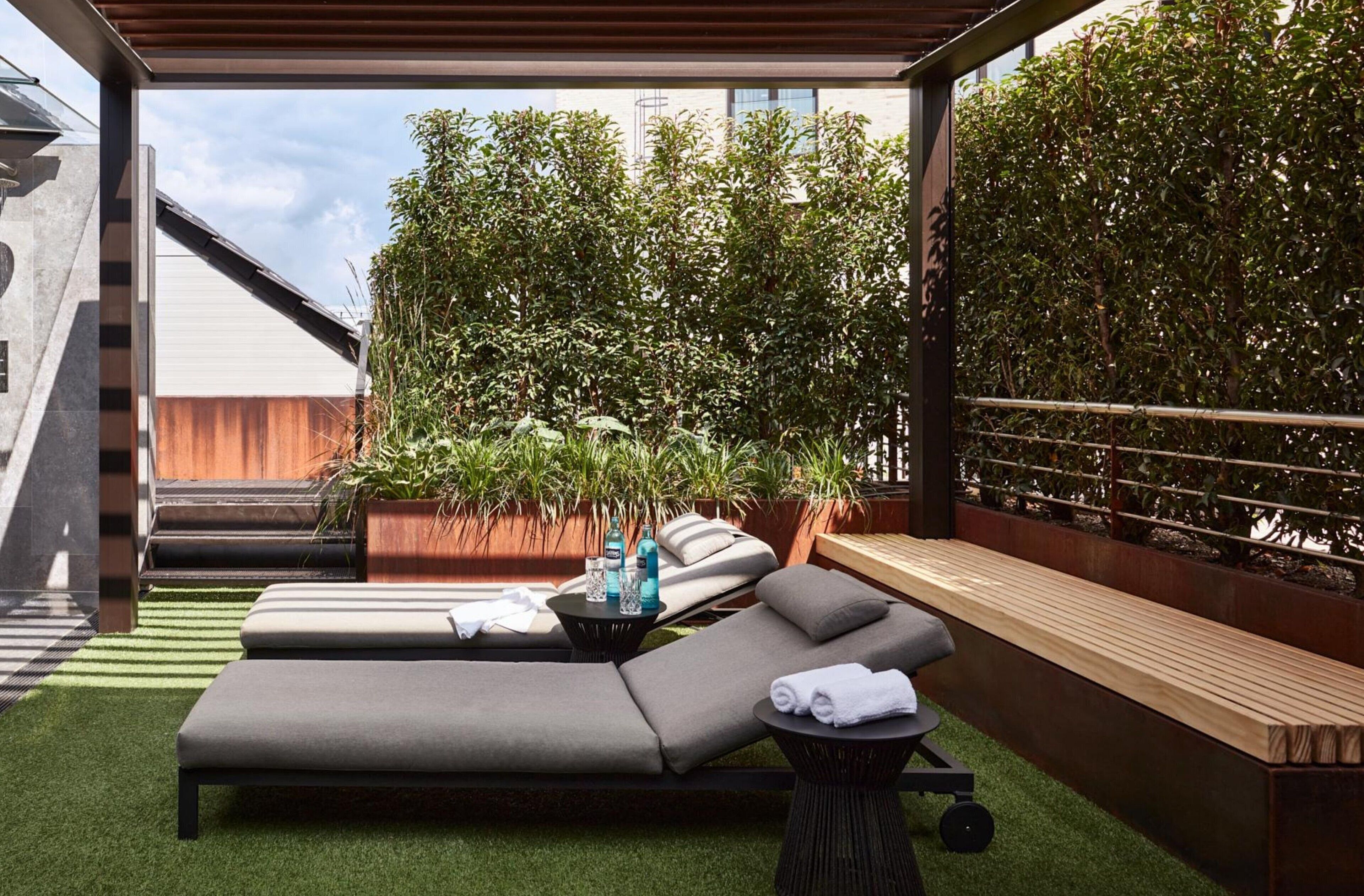 A modern outdoor lounge area with a pool, lounge chairs, and a wooden bench.